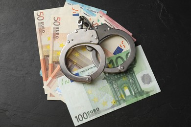 Corruption. Handcuffs and euro banknotes on grey textured table, flat lay