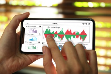 Image of Woman monitoring smart meter readings on mobile phone at home, closeup