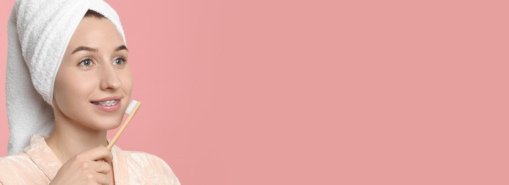 Image of Beautiful woman with braces brushing teeth on pink background. Banner design with space for text