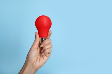 Image of Woman holding red bulb on light blue background, closeup. Space for text