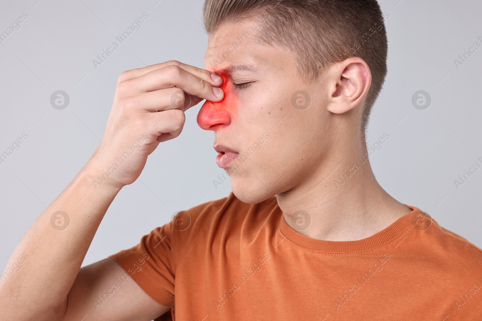 Image of Young man suffering from sinusitis on light grey background