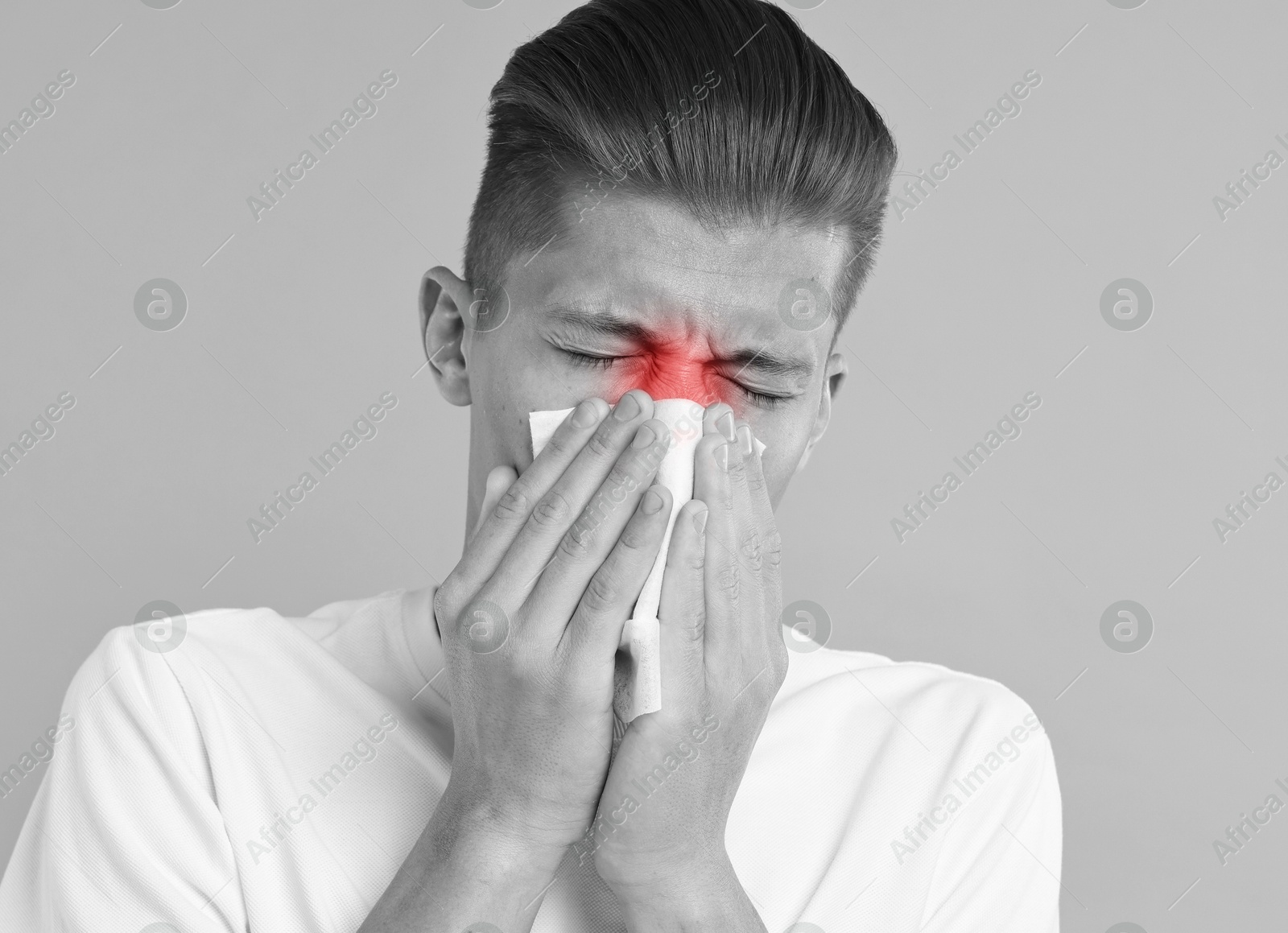 Image of Young man with tissue suffering from sinusitis. Black and white effect with red color accent