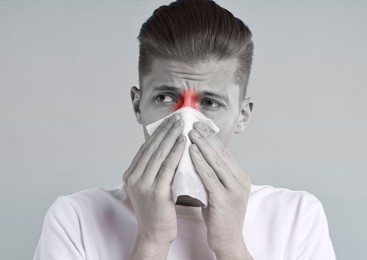 Image of Young man with tissue suffering from sinusitis. Black and white effect with red color accent