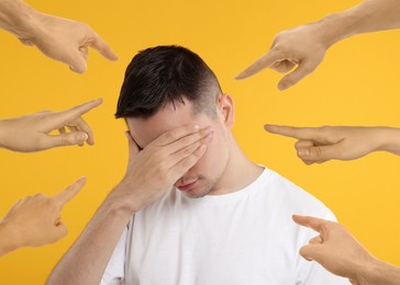 People pointing at embarrassed man on orange background