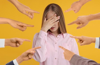 People pointing at embarrassed woman on orange background