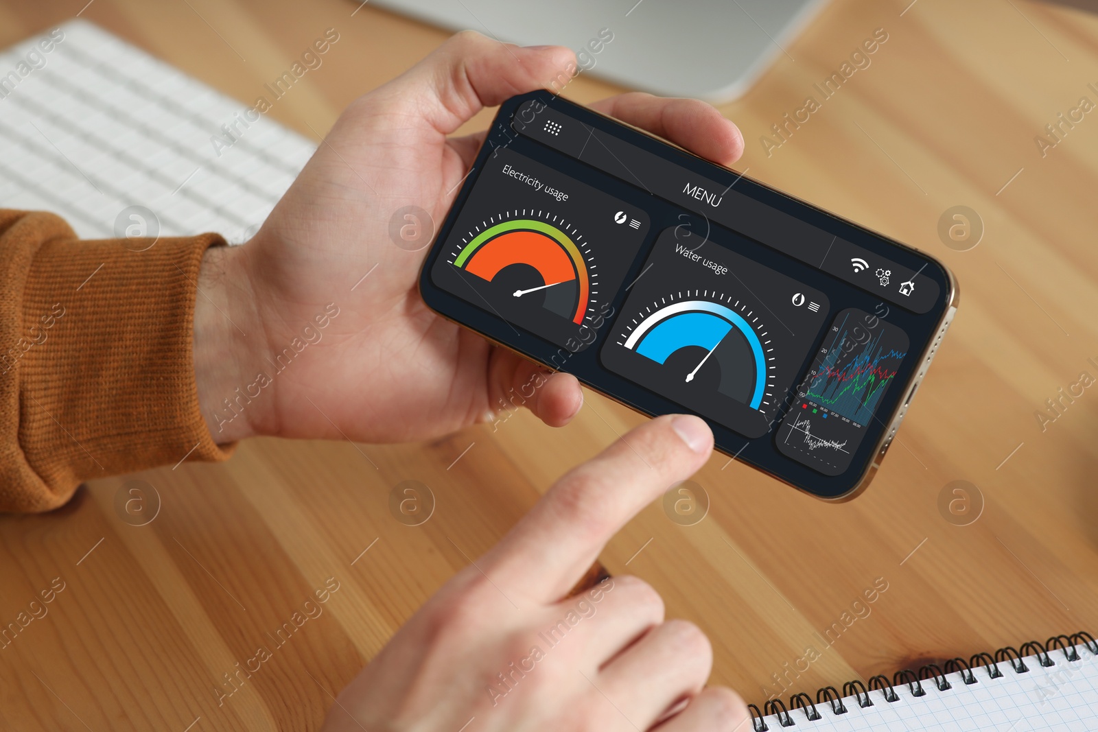 Image of Man monitoring smart meter readings on mobile phone at table, closeup