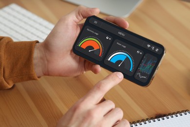 Image of Man monitoring smart meter readings on mobile phone at table, closeup