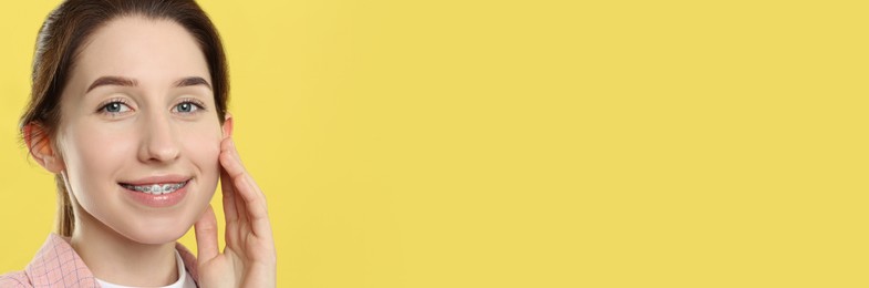 Image of Beautiful woman with braces smiling on yellow background. Banner design with space for text