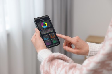 Woman monitoring smart meter readings on mobile phone at home, closeup