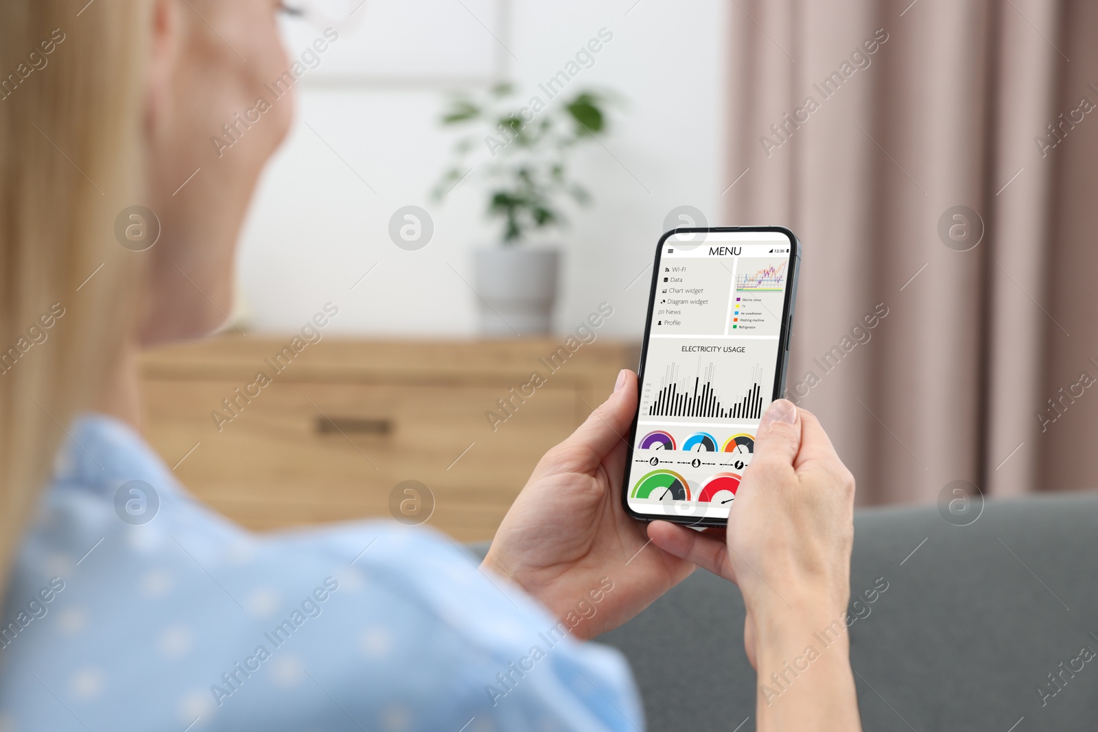 Image of Woman monitoring smart meter readings on mobile phone at home, closeup