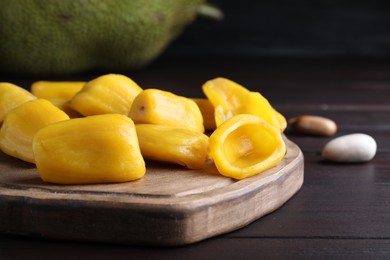 Photo of Fresh exotic jackfruit bulbs on black wooden table, closeup