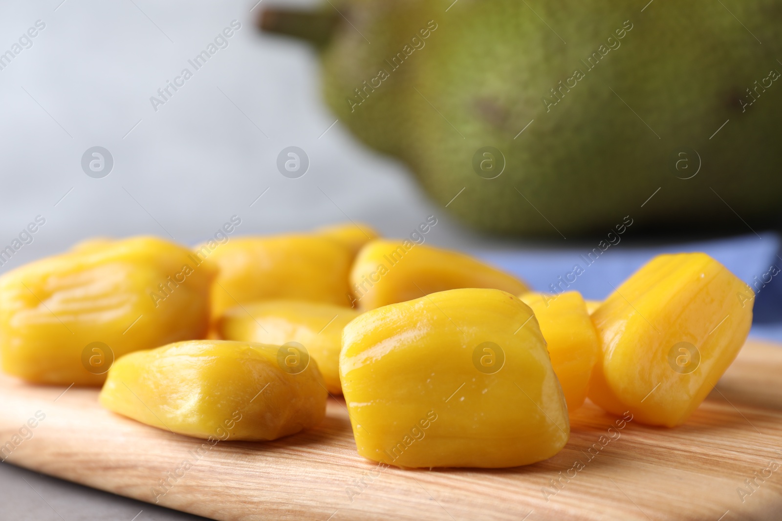 Photo of Delicious exotic jackfruit bulbs on wooden board, closeup