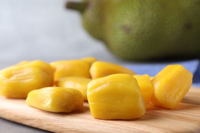 Photo of Delicious exotic jackfruit bulbs on wooden board, closeup