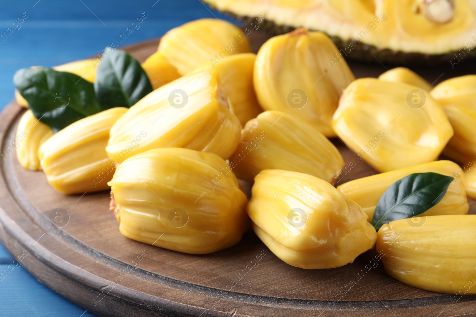 Photo of Delicious exotic jackfruit bulbs on wooden board, closeup