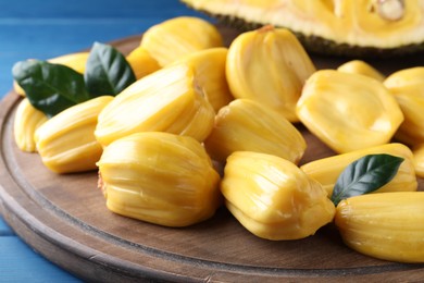 Photo of Delicious exotic jackfruit bulbs on wooden board, closeup