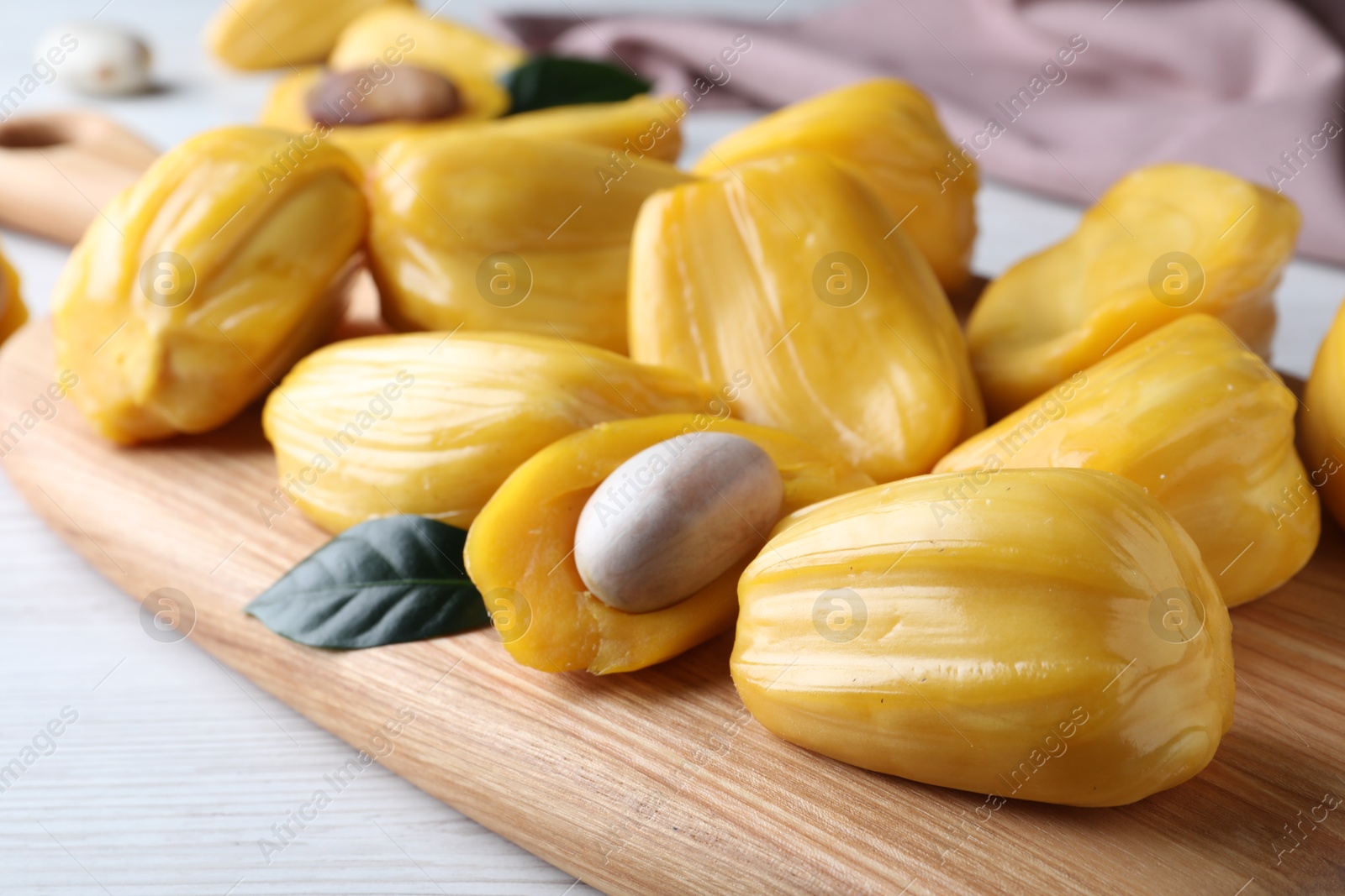 Photo of Delicious exotic jackfruit bulbs on white wooden table, closeup