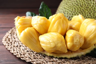 Photo of Fresh exotic jackfruit bulbs on wooden table, closeup