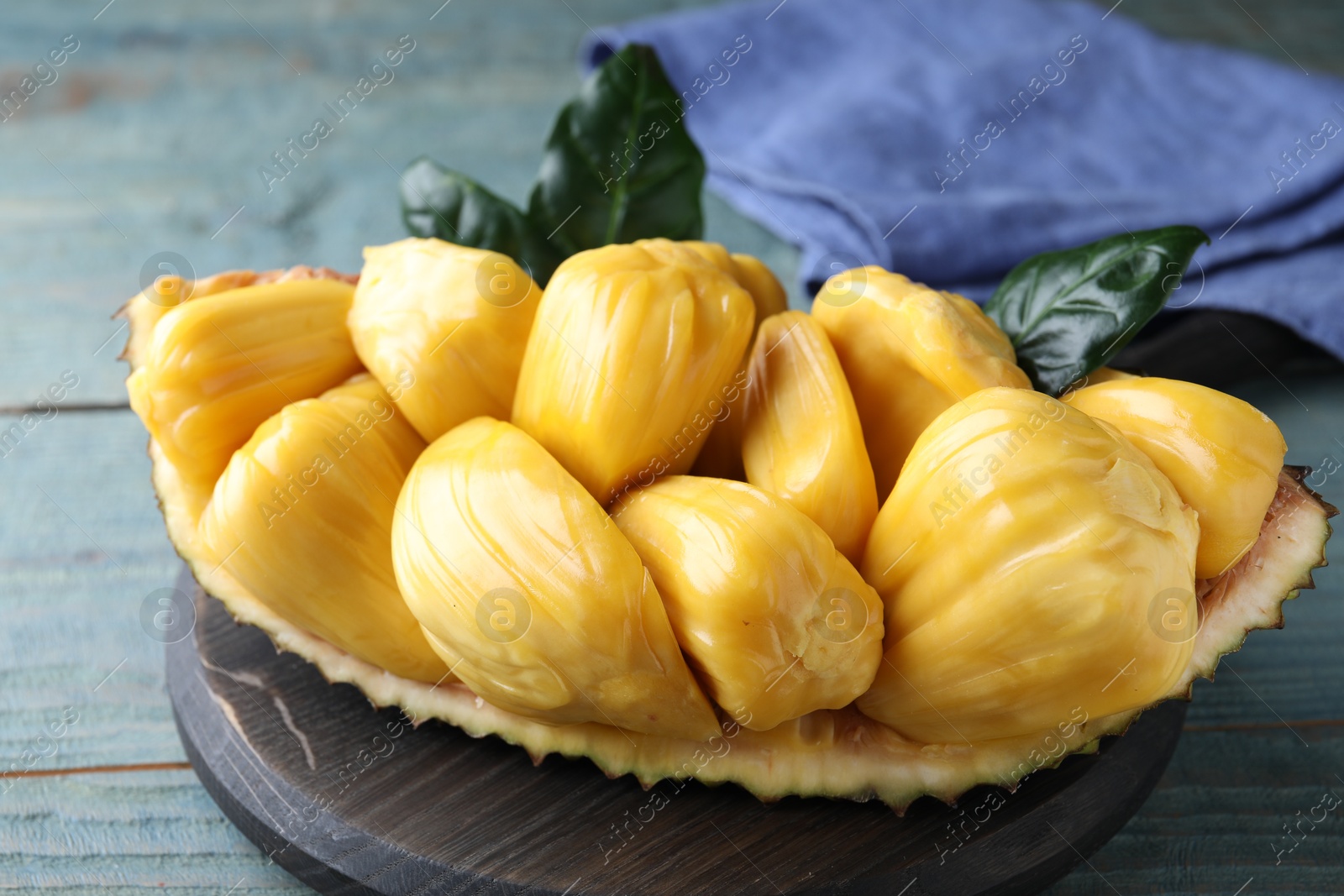 Photo of Fresh exotic jackfruit bulbs on light blue wooden table