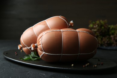 Photo of Tasty boiled sausages on black textured table, closeup