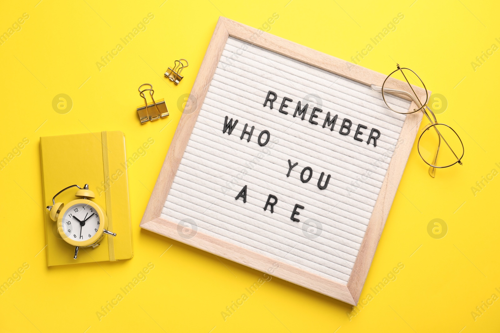 Photo of Flat lay composition of letter board with phrase Remember Who You Are on yellow background