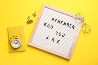 Photo of Flat lay composition of letter board with phrase Remember Who You Are on yellow background