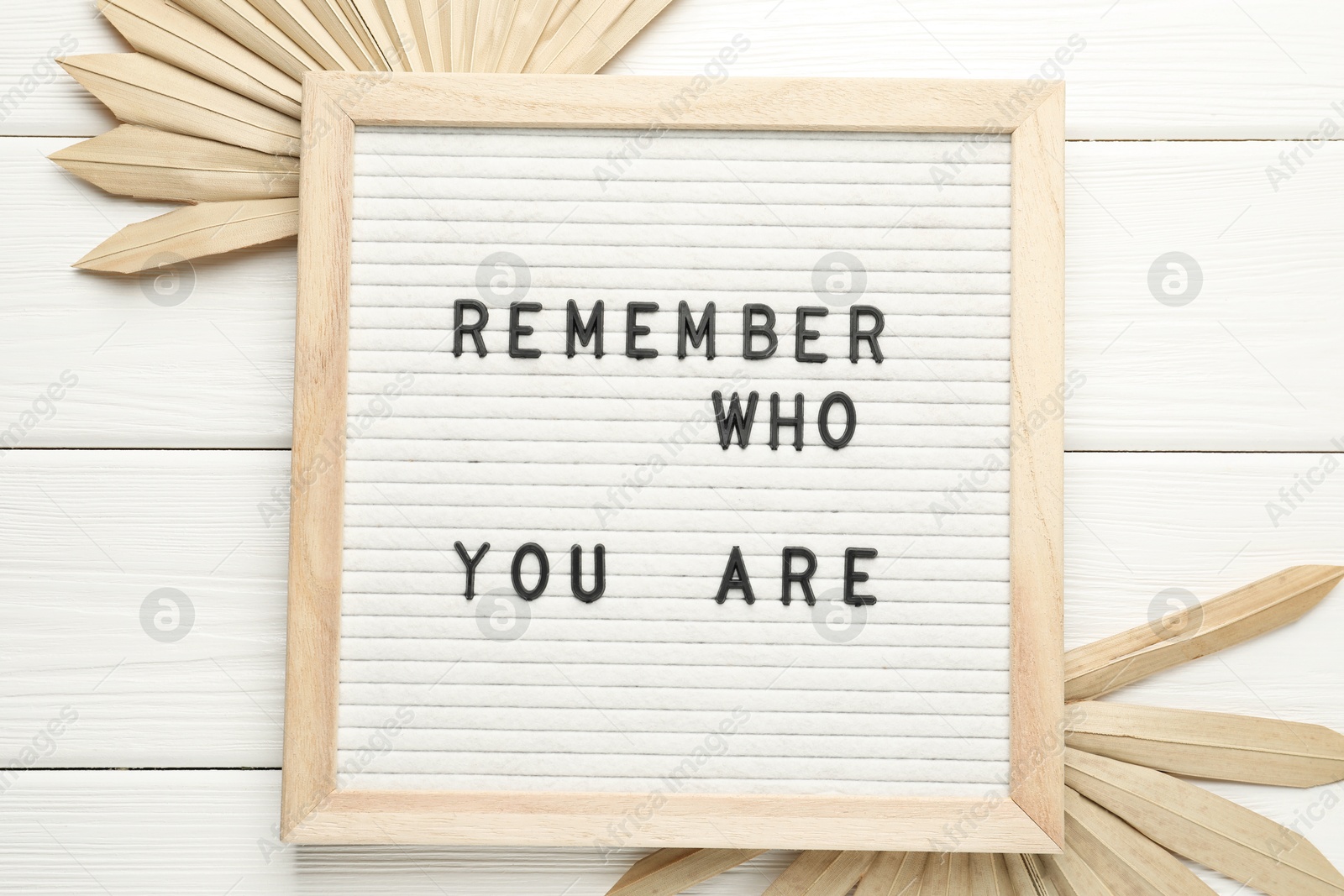 Photo of Letter board with phrase Remember Who You Are and decor elements on white wooden table, flat lay