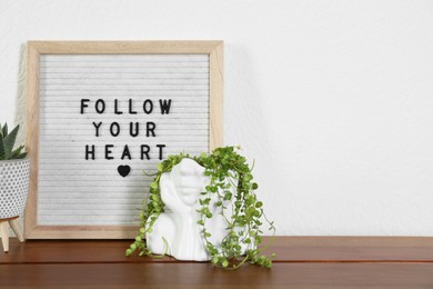 Photo of Letter board with phrase Follow Your Heart and plants on wooden table, space for text