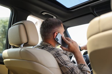 Man talking on smartphone while driving car