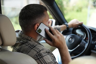 Man talking on smartphone while driving car