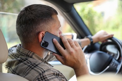 Man talking on smartphone while driving car