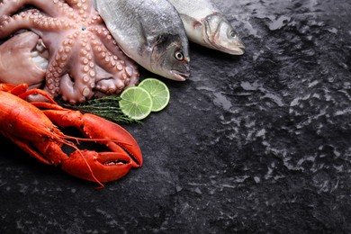 Photo of Sea food. Fresh raw octopus, fish and lobster on black table, flat lay. Space for text