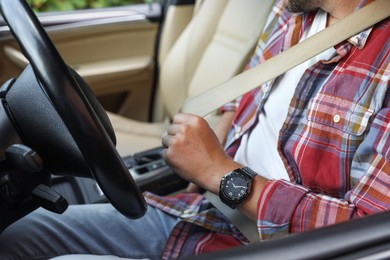 Man fastening safety seat inside car, closeup