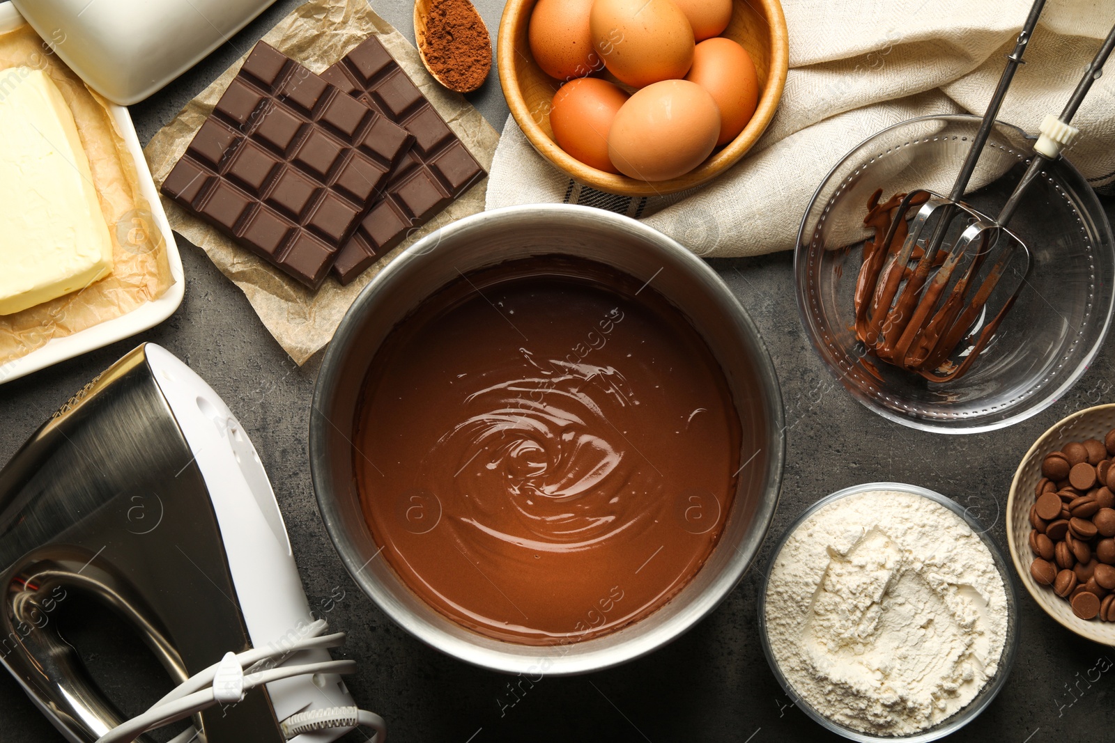 Photo of Chocolate dough in bowl and ingredients on grey table, flat lay