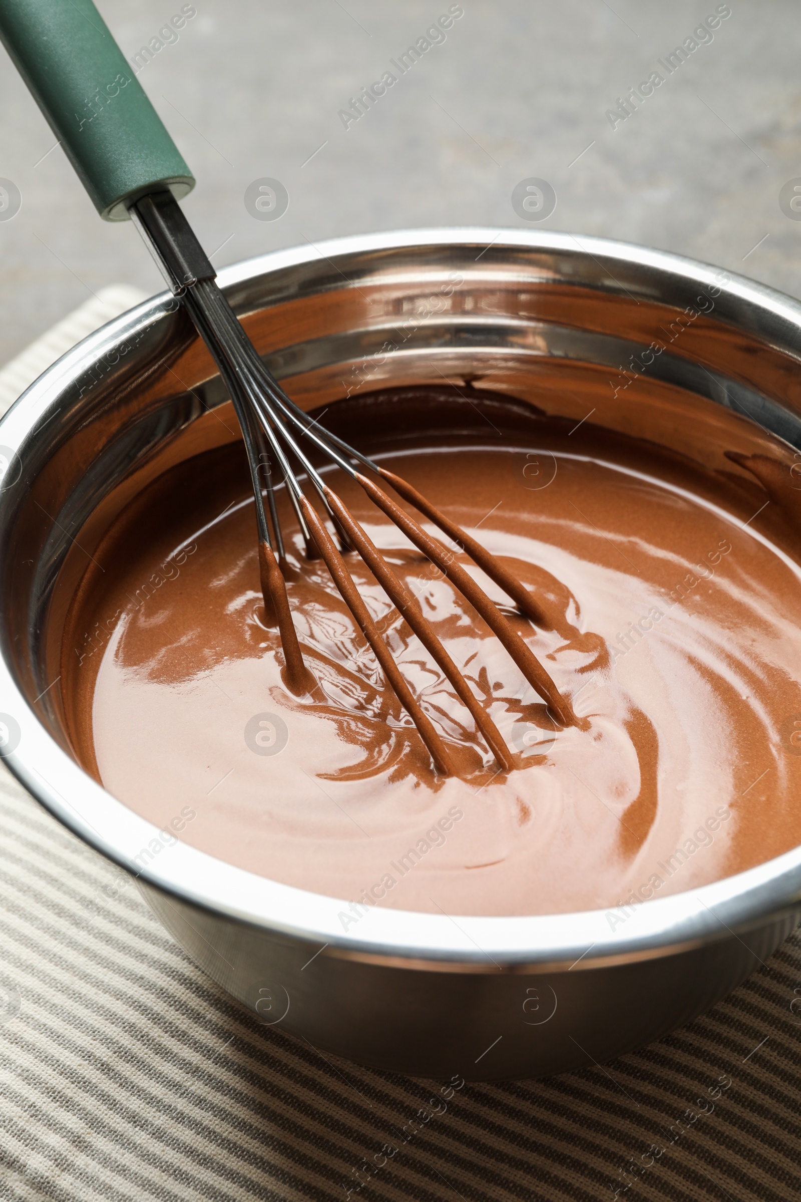 Photo of Chocolate dough and whisk in bowl on grey table, closeup