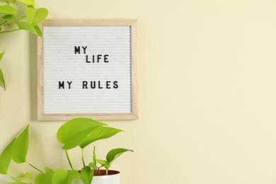 Photo of Letter board with phrase My Life My Rules and plant on beige wall. Space for text