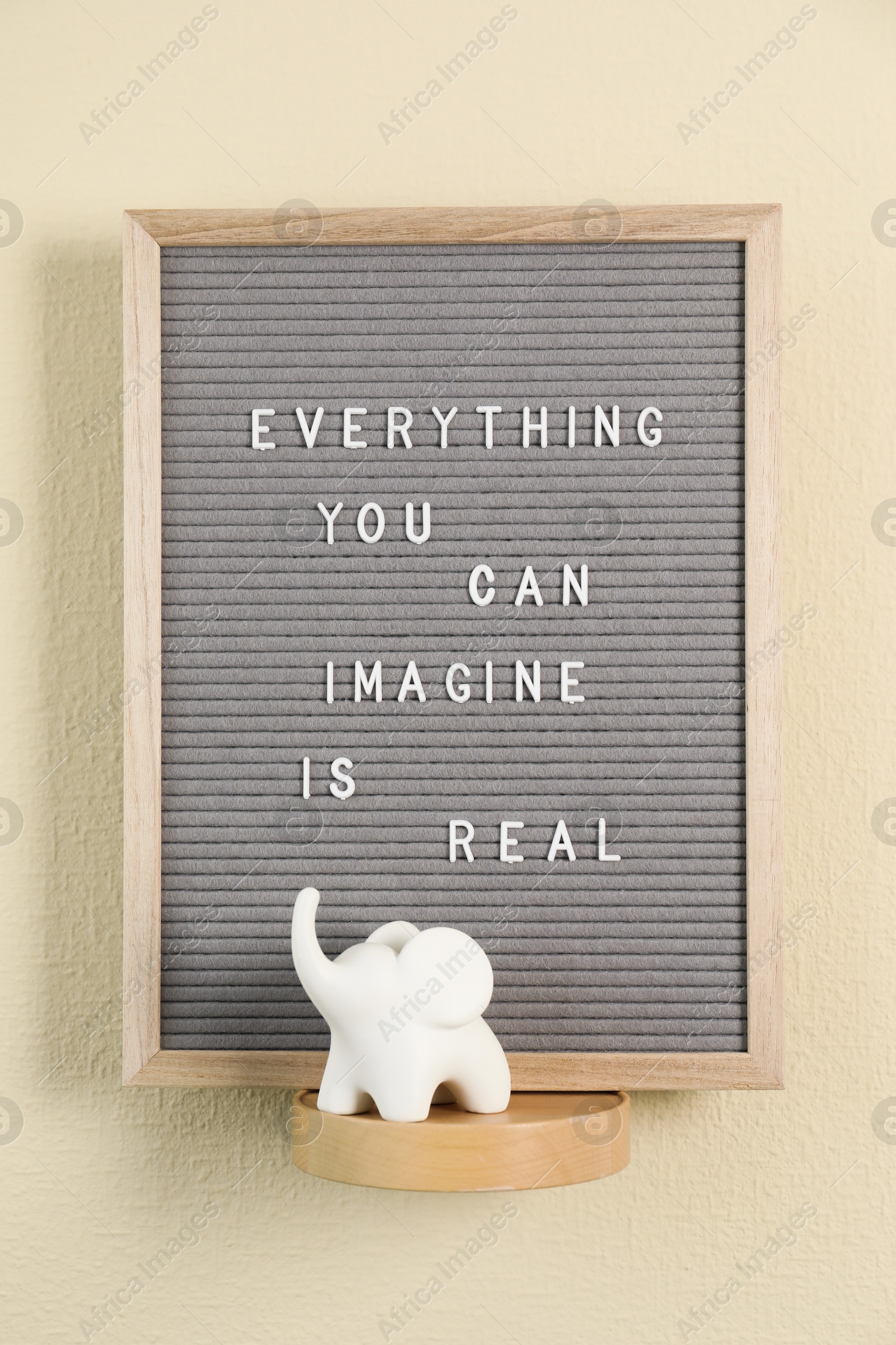 Photo of Letter board with phrase Everything You Can Imagine Is Real and decor element on beige wall