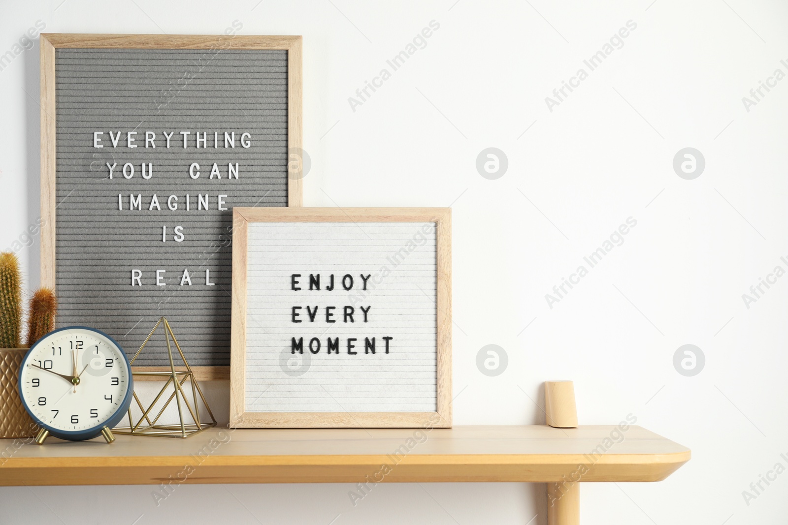 Photo of Letter boards with phrases Everything You Can Imagine Is Real, Enjoy Every moment and decor elements on wooden table