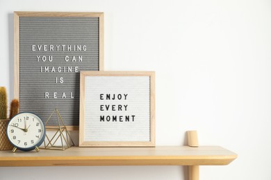 Photo of Letter boards with phrases Everything You Can Imagine Is Real, Enjoy Every moment and decor elements on wooden table