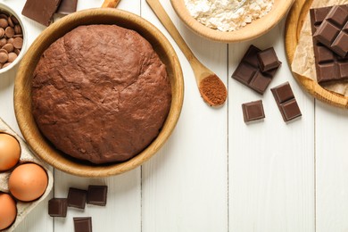 Photo of Chocolate dough and ingredients on white wooden table, flat lay