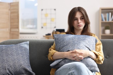 Loneliness concept. Sad teenage girl with pillow on sofa at home