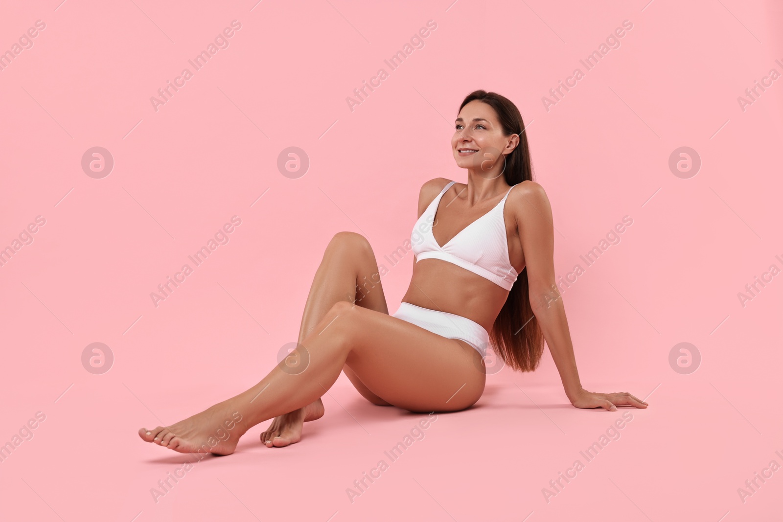 Photo of Smiling woman with perfect skin posing on pink background. Body care