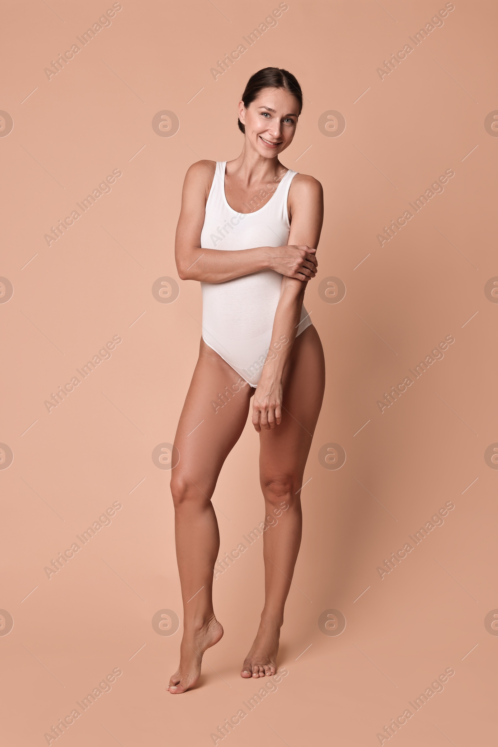 Photo of Smiling woman with perfect skin on beige background. Body care