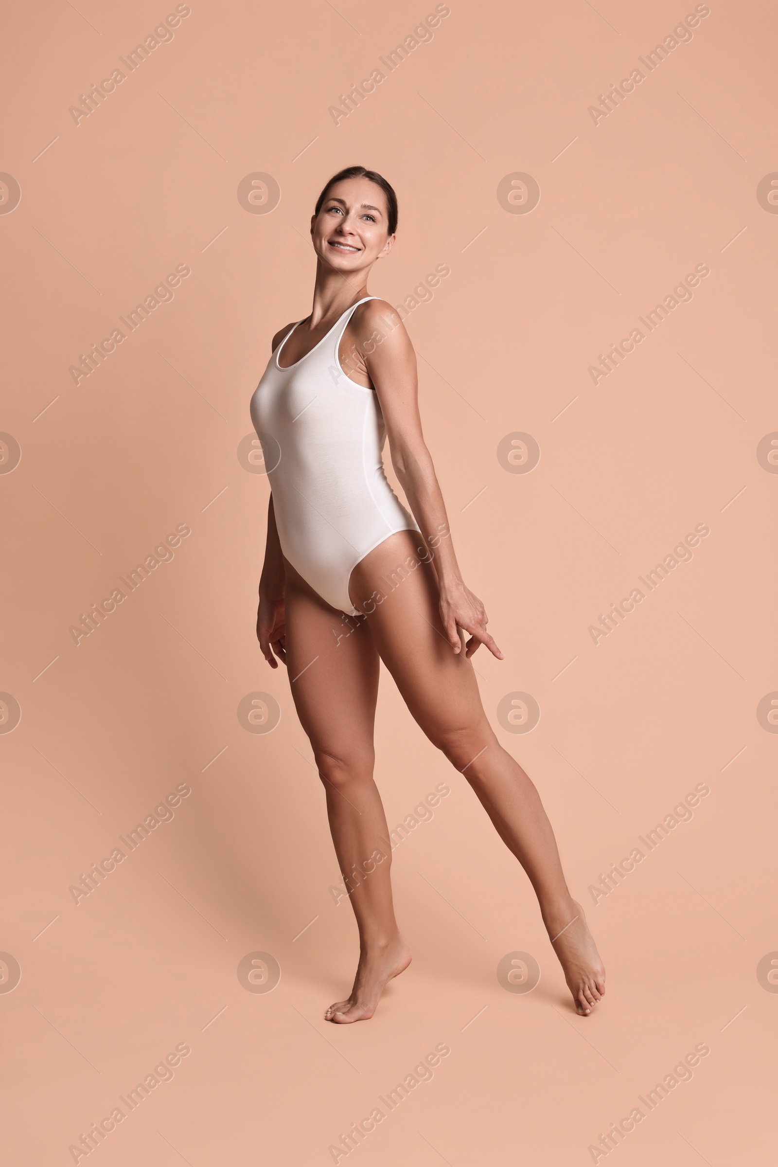 Photo of Smiling woman with perfect skin posing on beige background. Body care