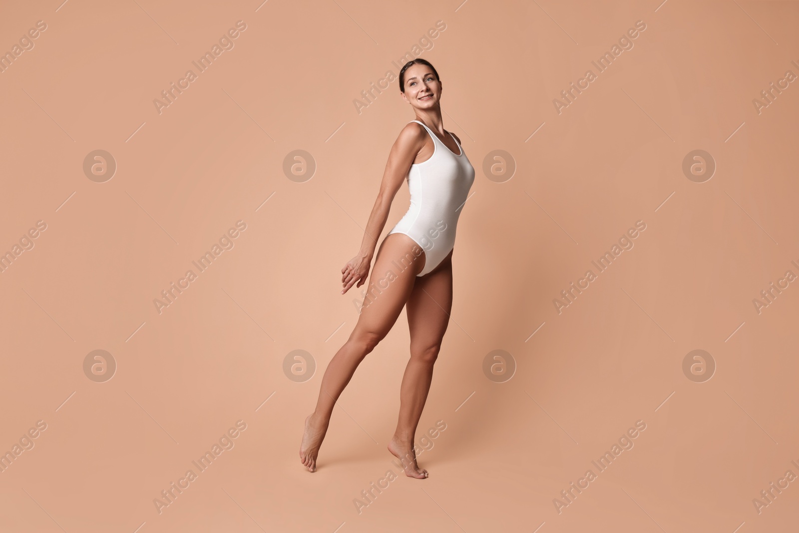 Photo of Smiling woman with perfect skin posing on beige background. Body care