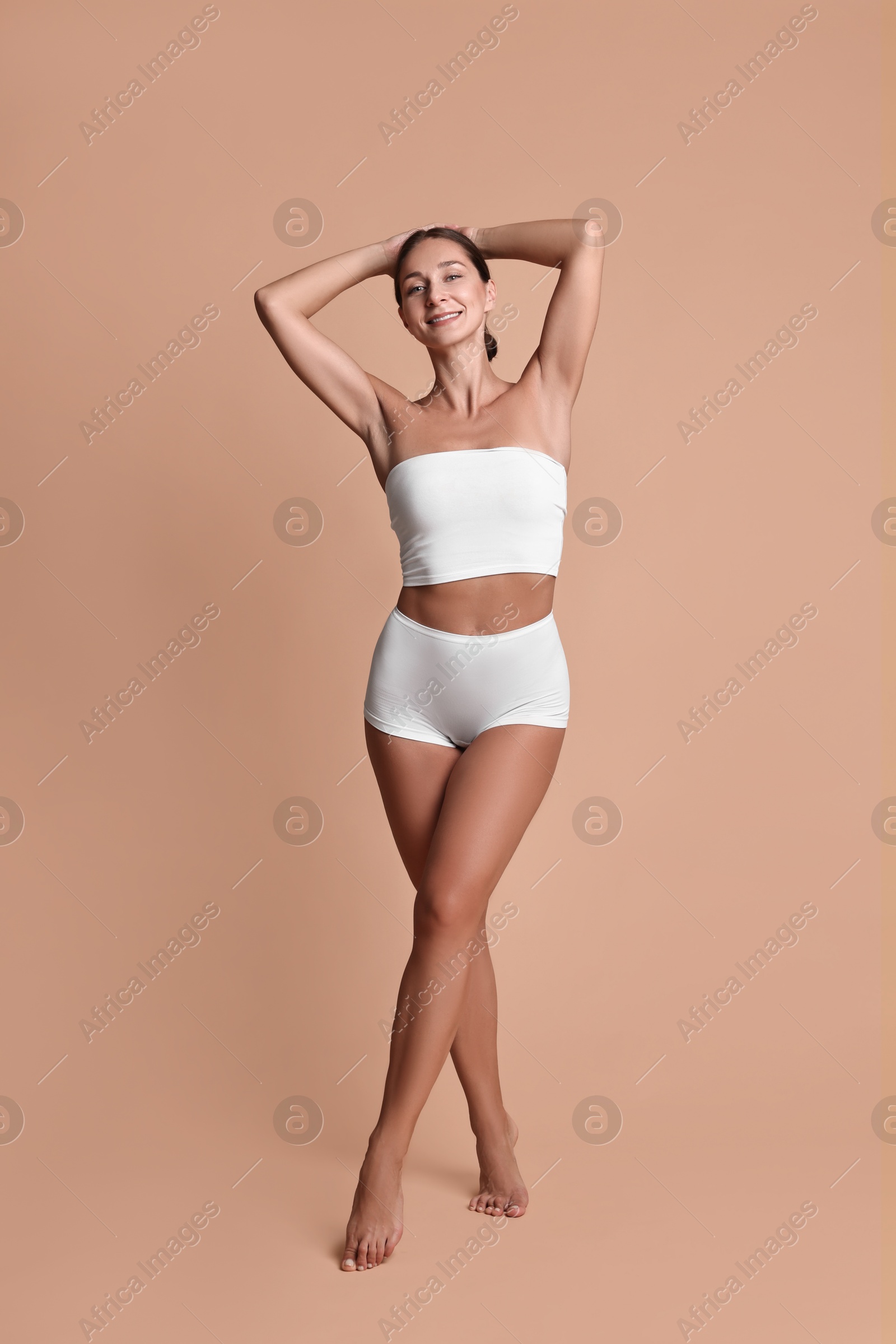 Photo of Smiling woman with perfect skin posing on beige background. Body care