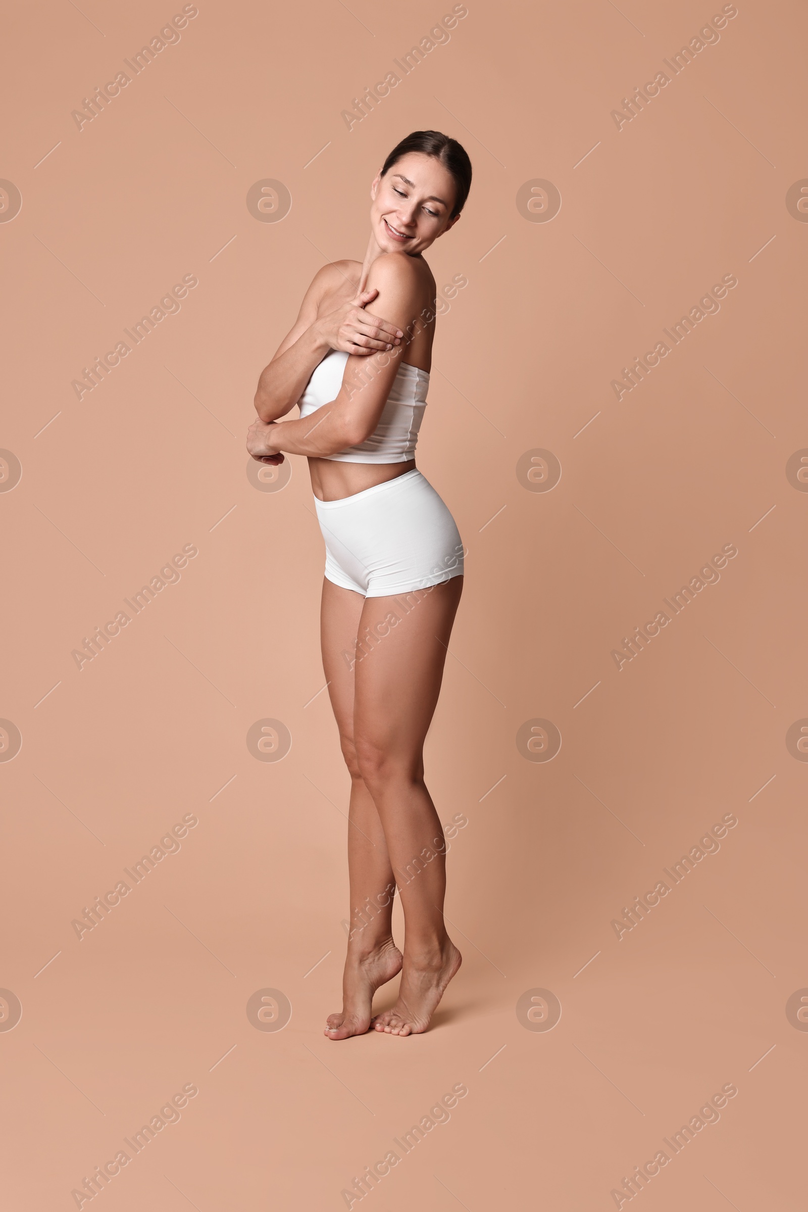 Photo of Smiling woman with perfect skin posing on beige background. Body care