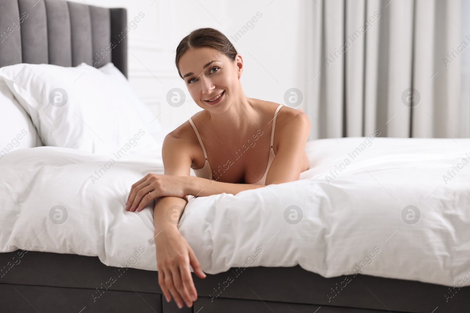 Photo of Smiling woman with perfect skin posing on bed. Body care