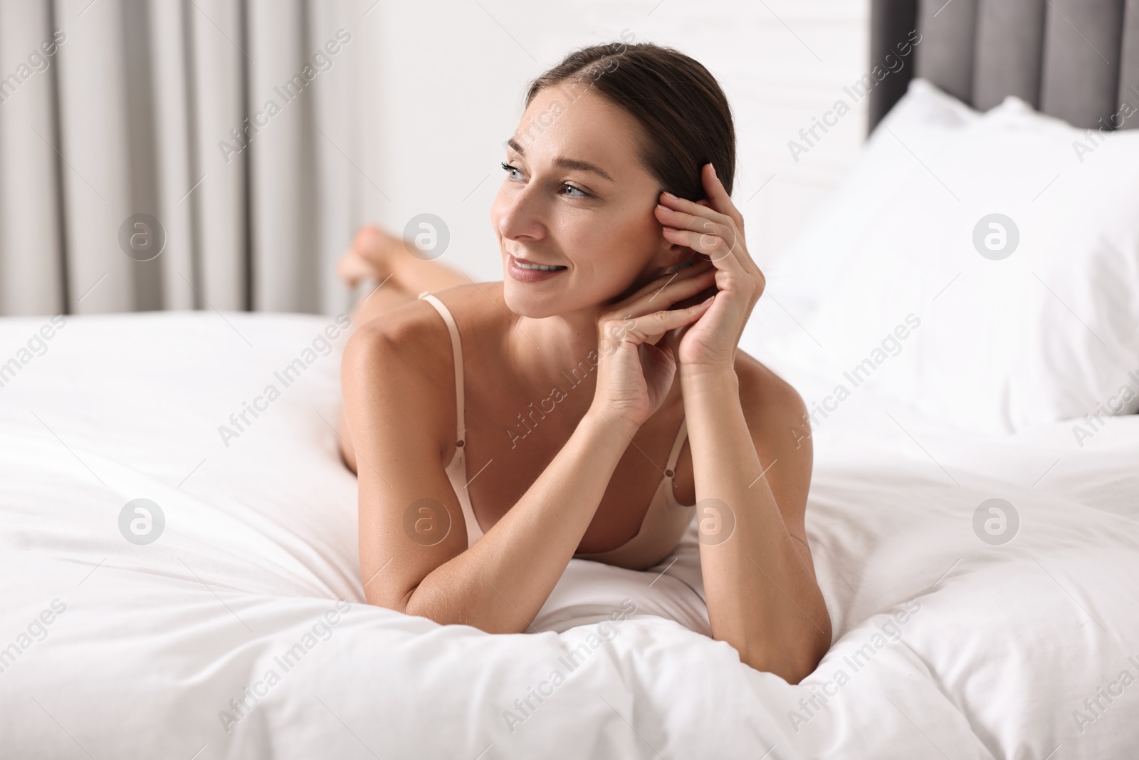 Photo of Smiling woman with perfect skin posing on bed. Body care