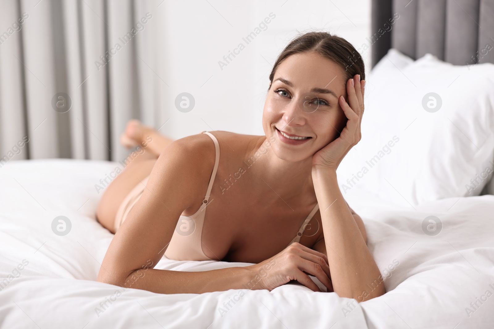 Photo of Smiling woman with perfect skin posing on bed. Body care