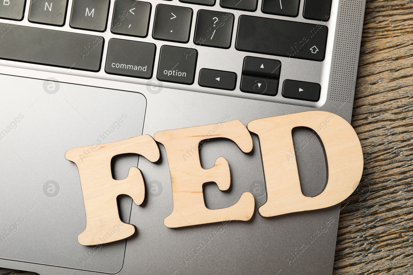 Photo of Wooden letters Fed (Federal Reserve System) and laptop on table, flat lay